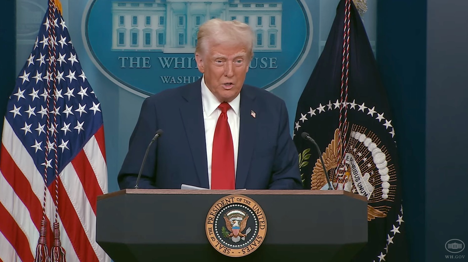 a man in a suit and tie standing at a podium