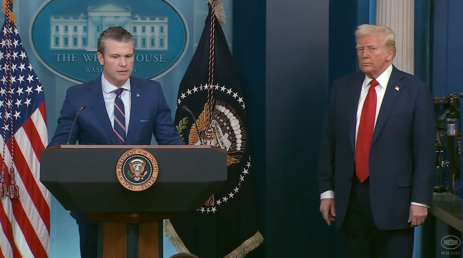 a man standing at a podium with a man in a suit