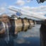 a man in a suit and tie standing in front of a body of water