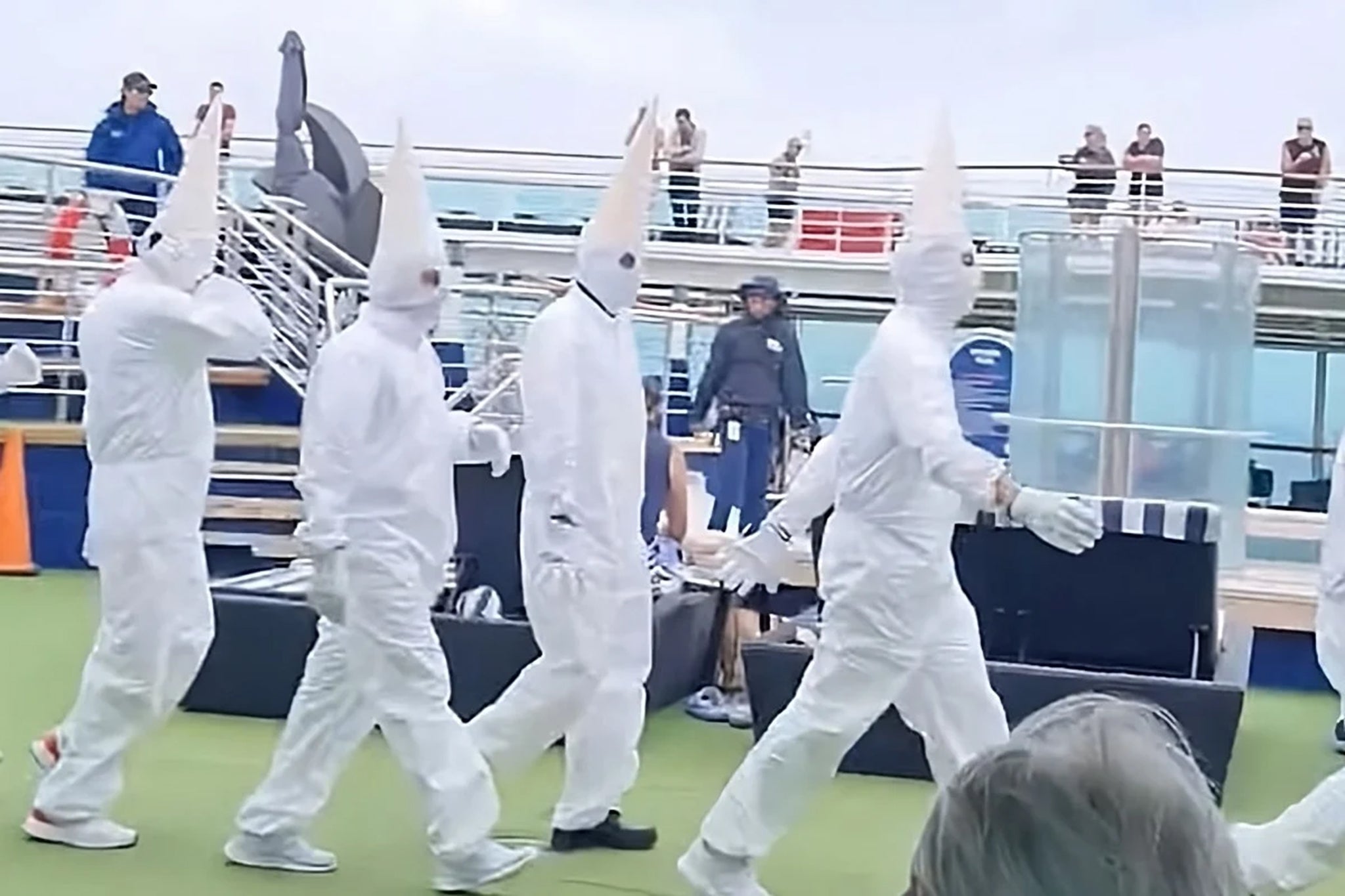 a group of people in white clothing walking on a deck