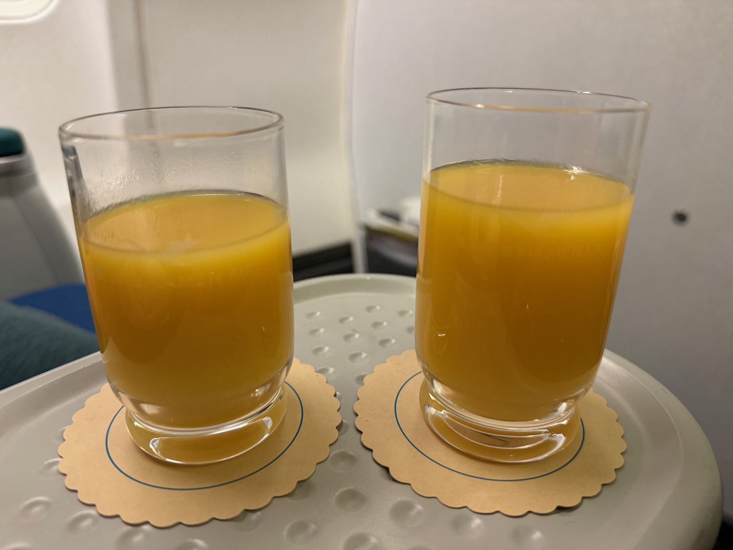 two glasses of orange juice on coasters