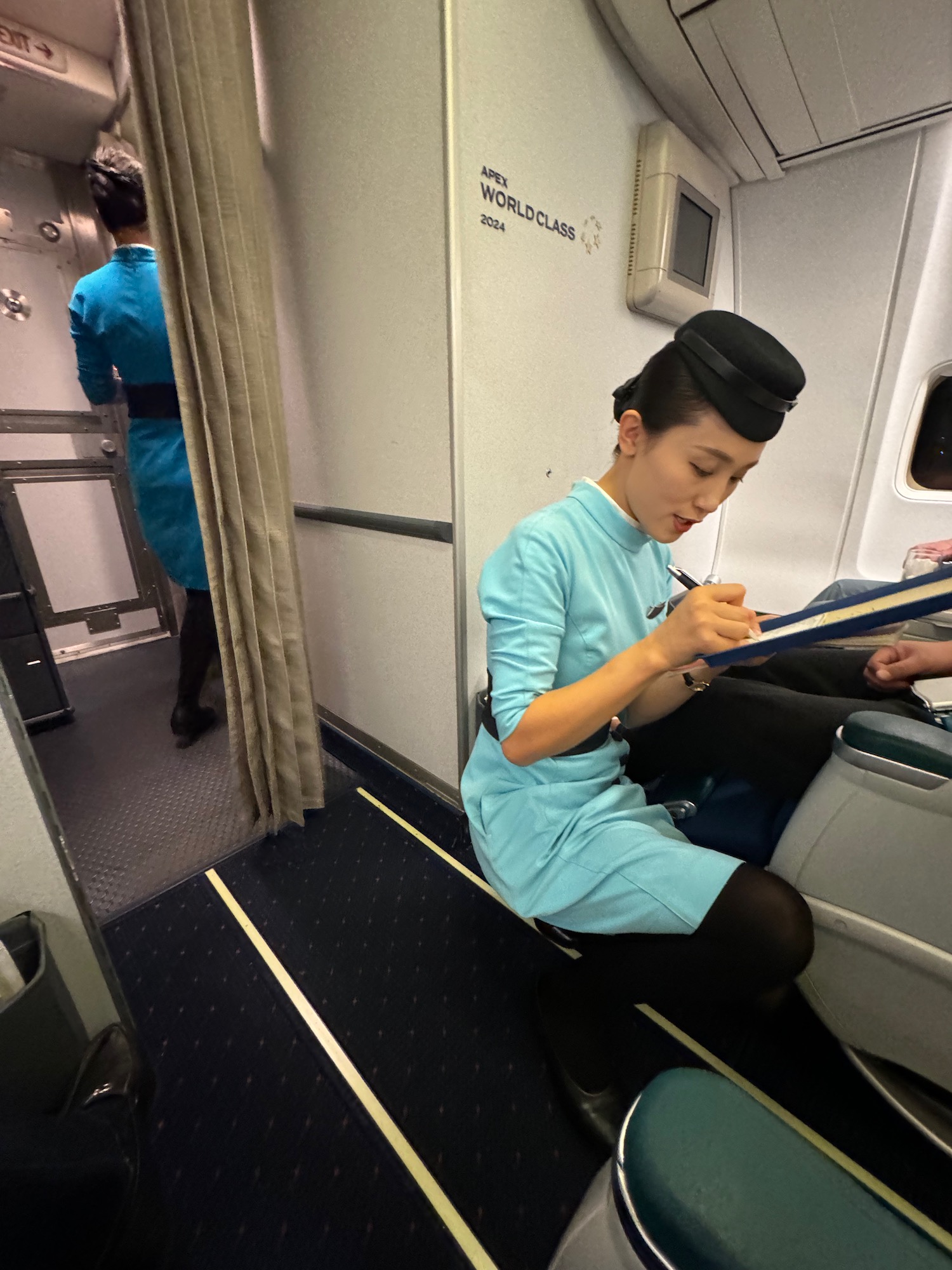 a woman sitting on a plane writing on a clipboard