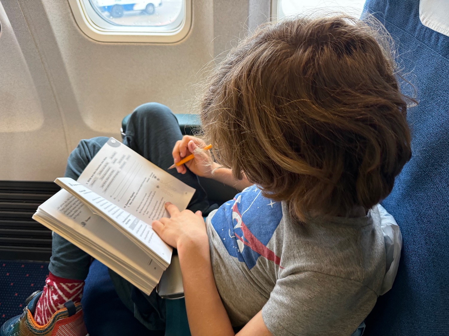 a child sitting on a plane reading a book