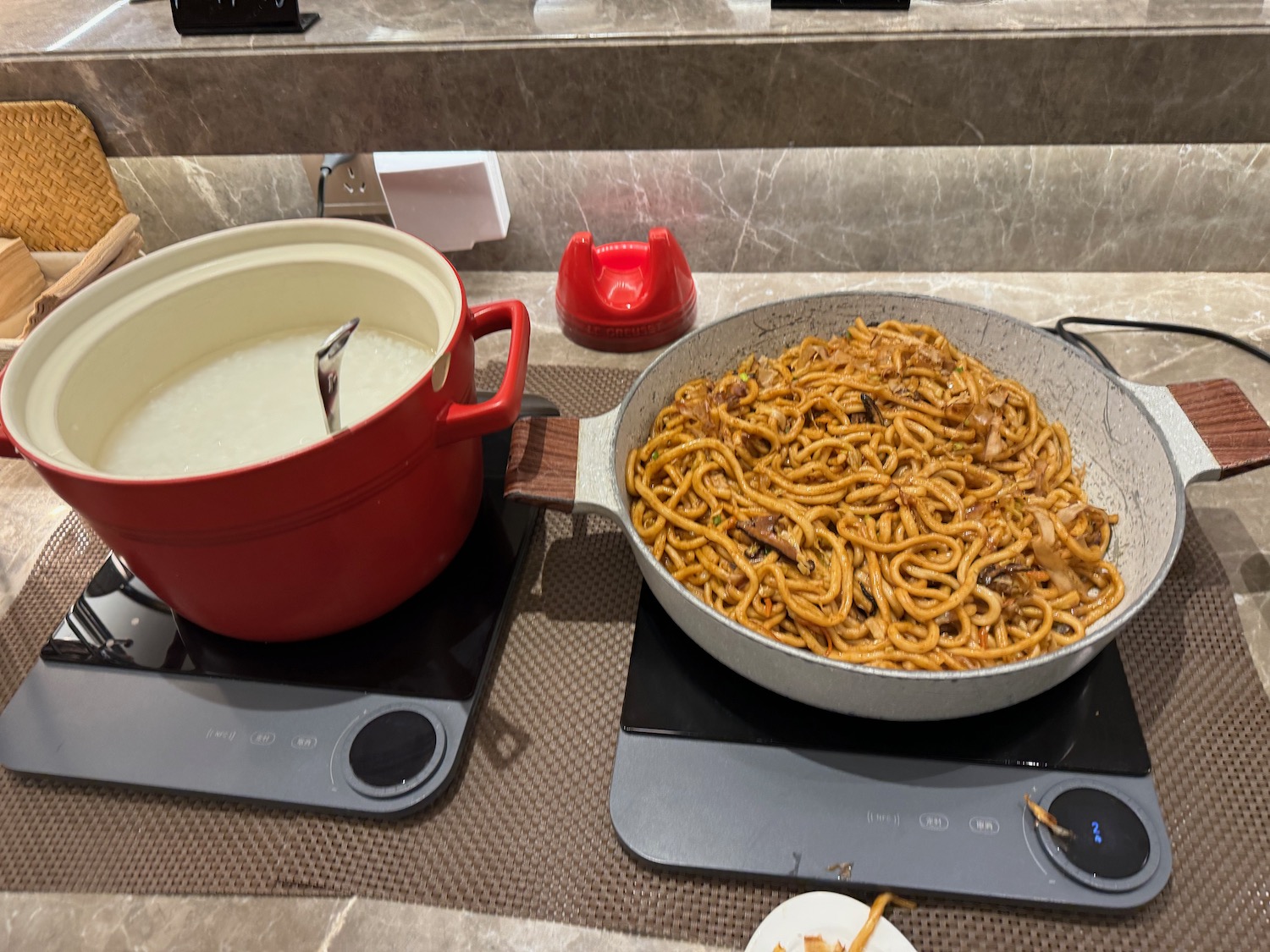 a pan of noodles and a pot of liquid on a stove