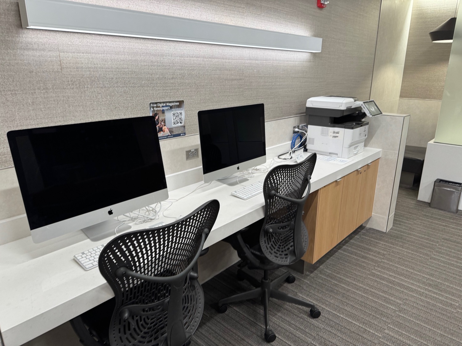 a desk with computers and chairs in a room