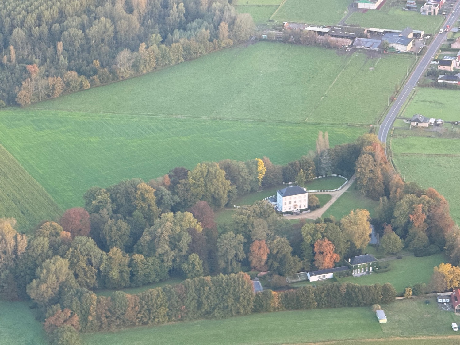 a green field with trees and buildings