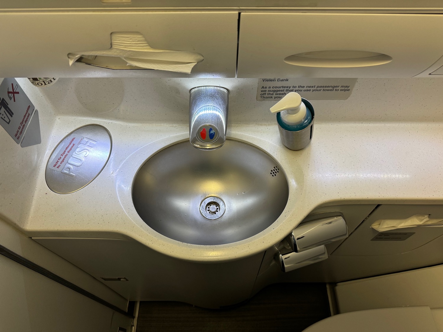 a sink with soap dispenser and a toilet