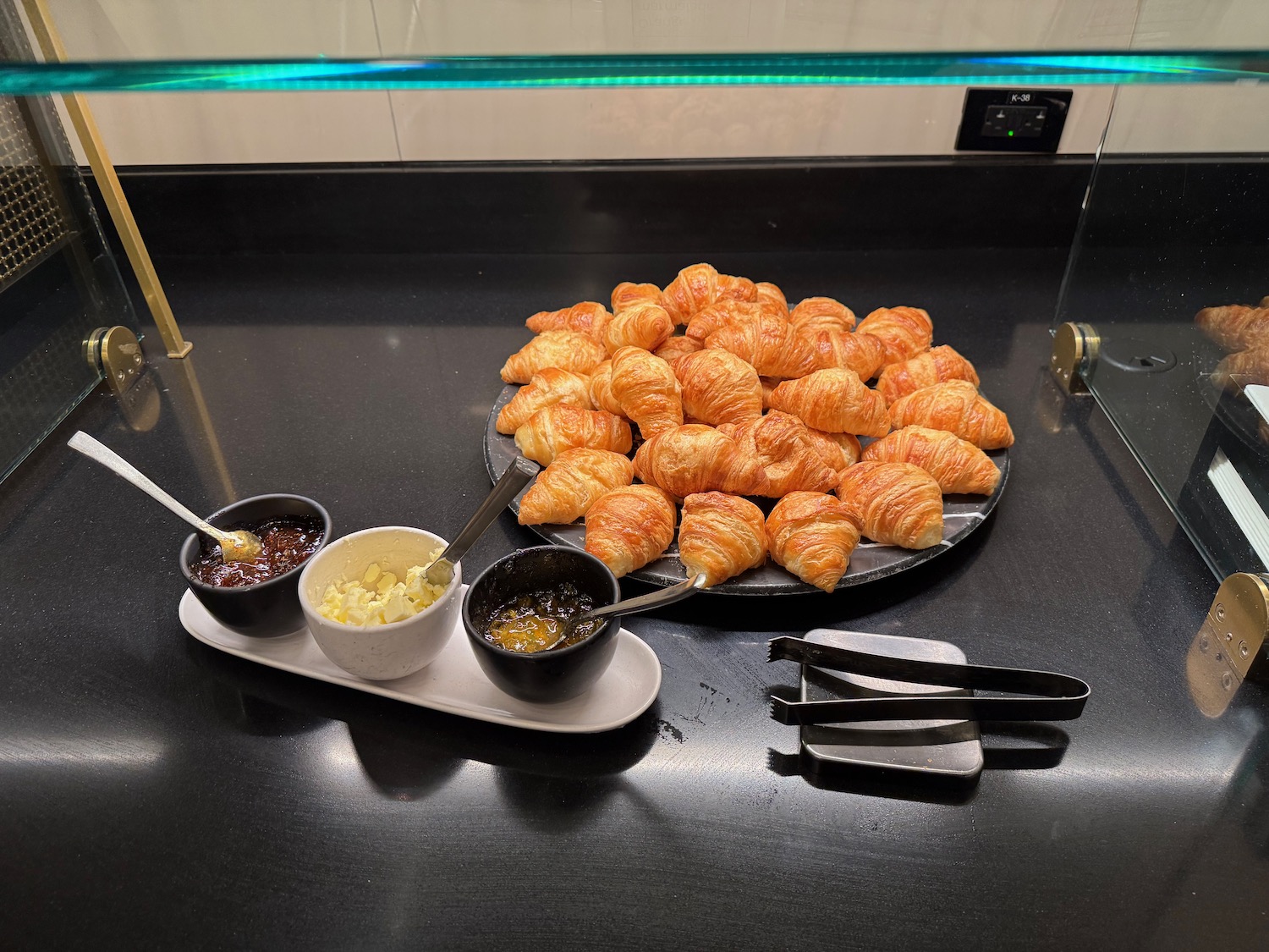 a plate of croissants and bowls of jam