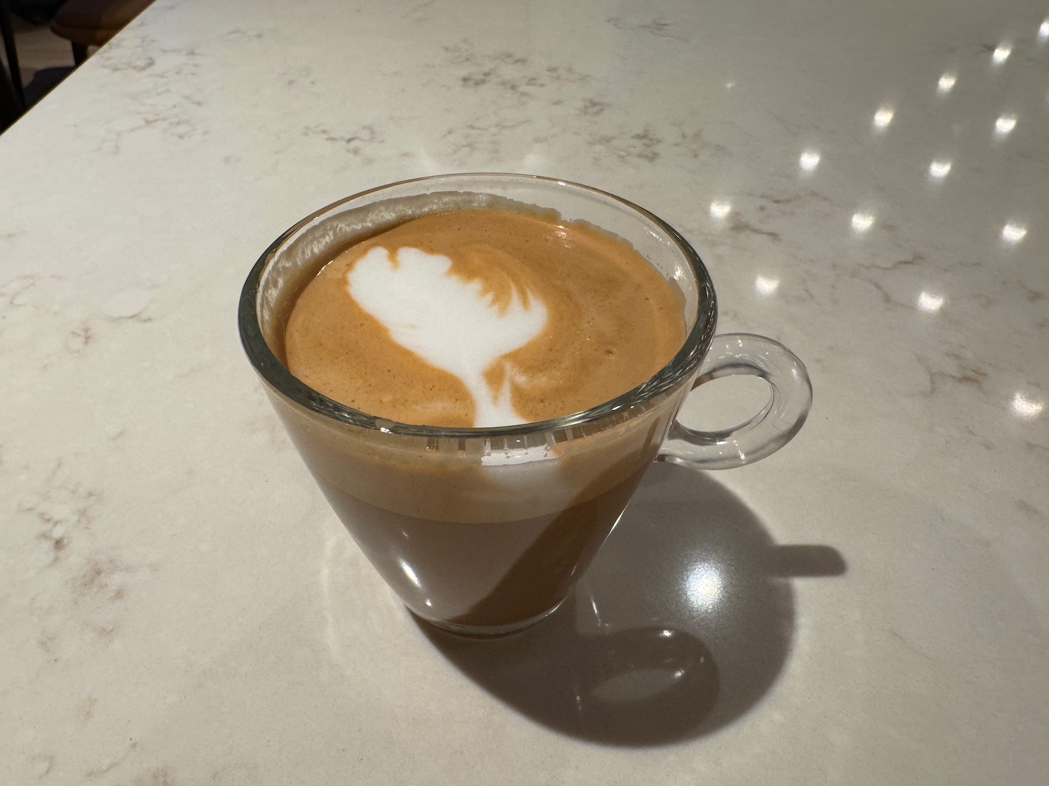 a glass cup of coffee with a white and brown foam