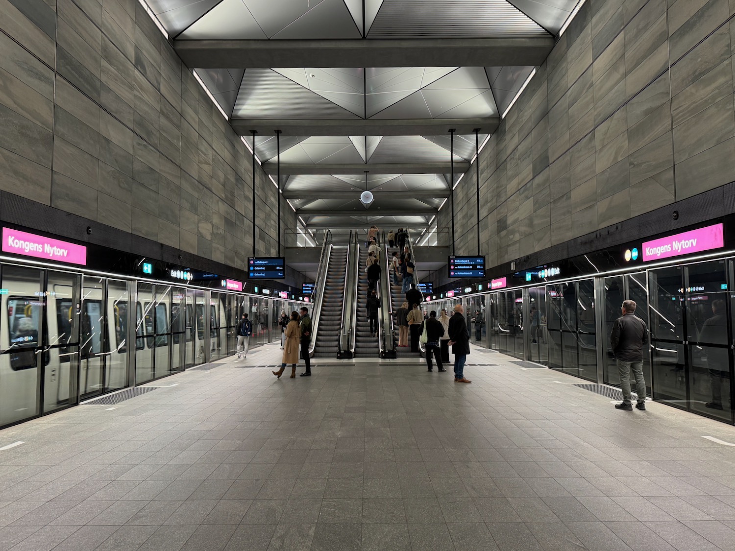 people standing on escalators in a subway station