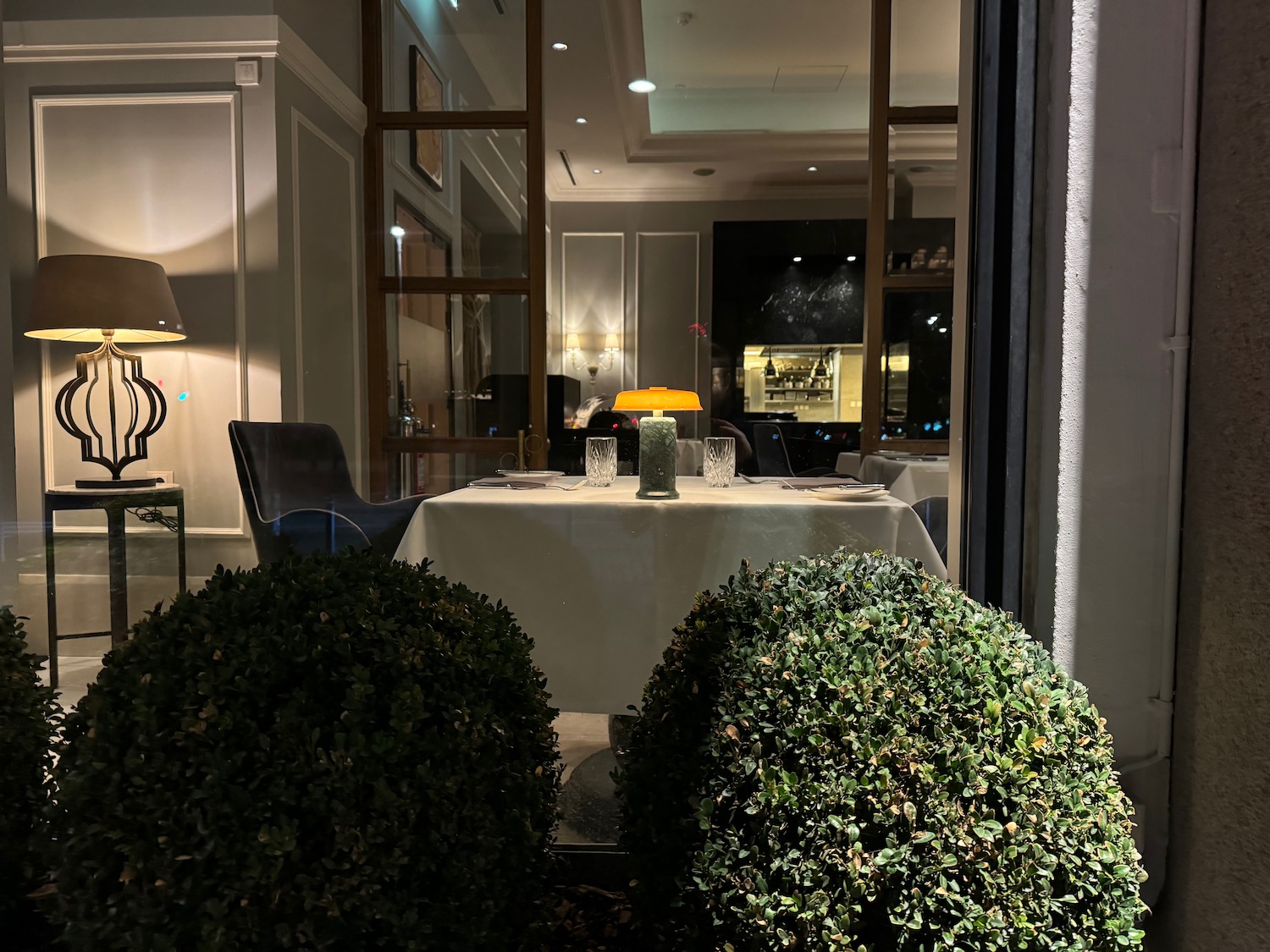 a table with a white tablecloth and two bushes in front of it