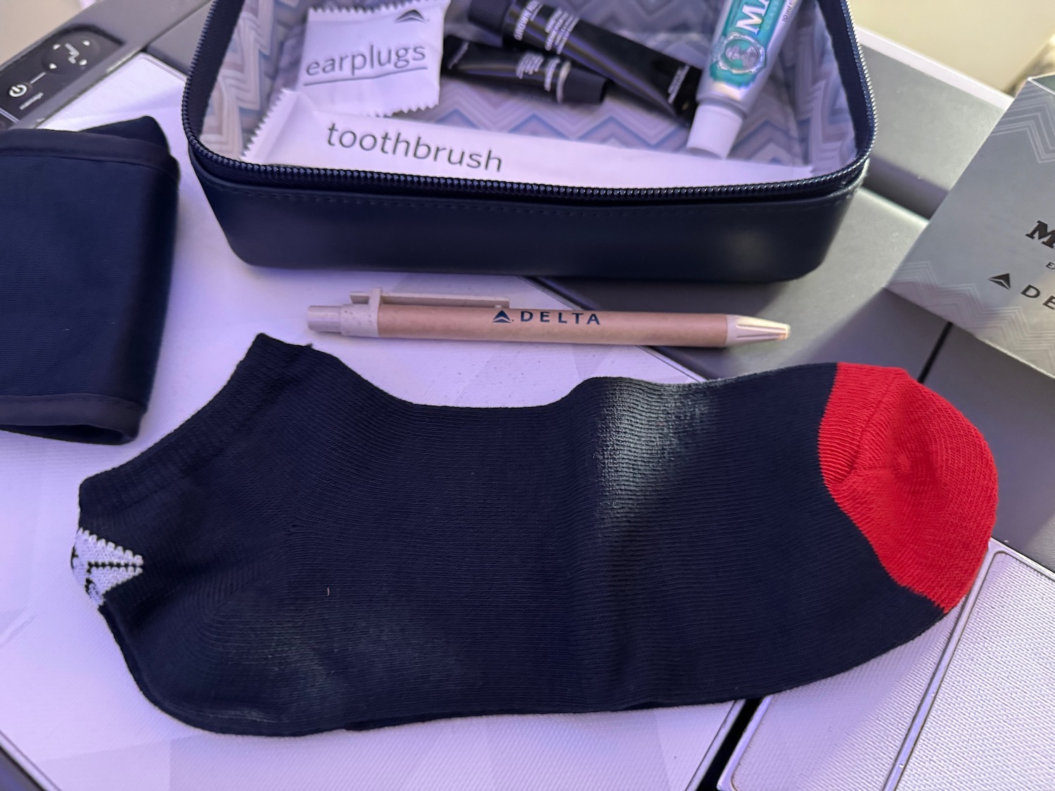 a black sock and a red sock next to a black case with toothpaste and toothbrushes