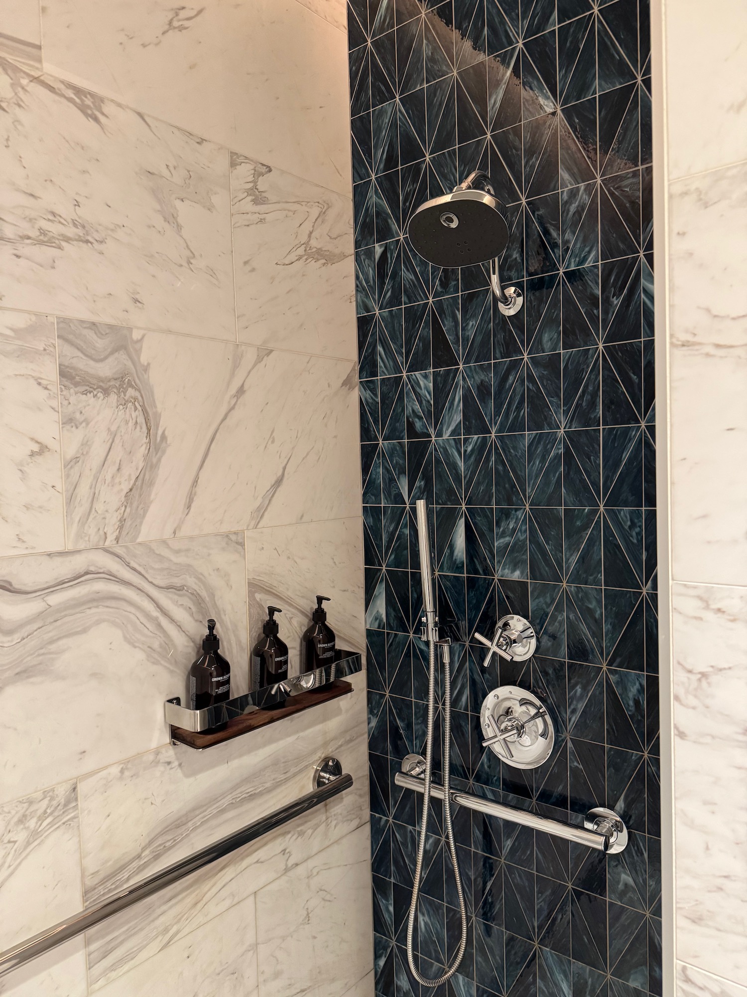 a shower with a black tile wall and a silver shower head