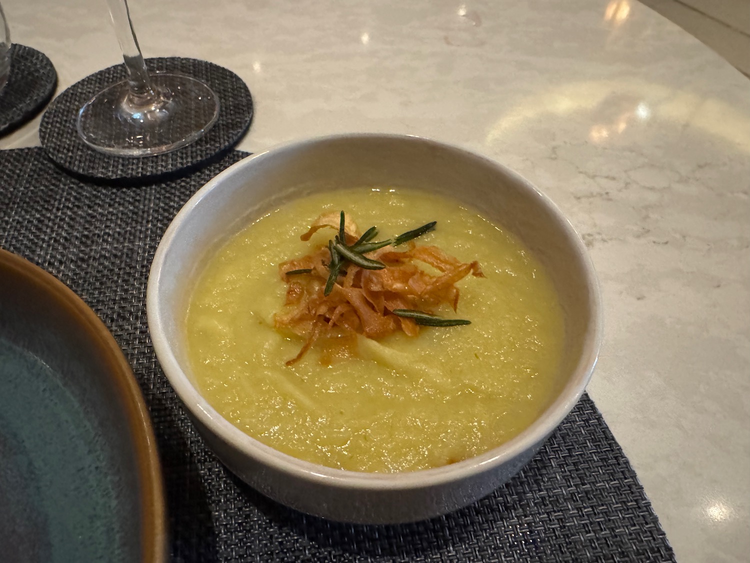 a bowl of soup with a sprig of rosemary