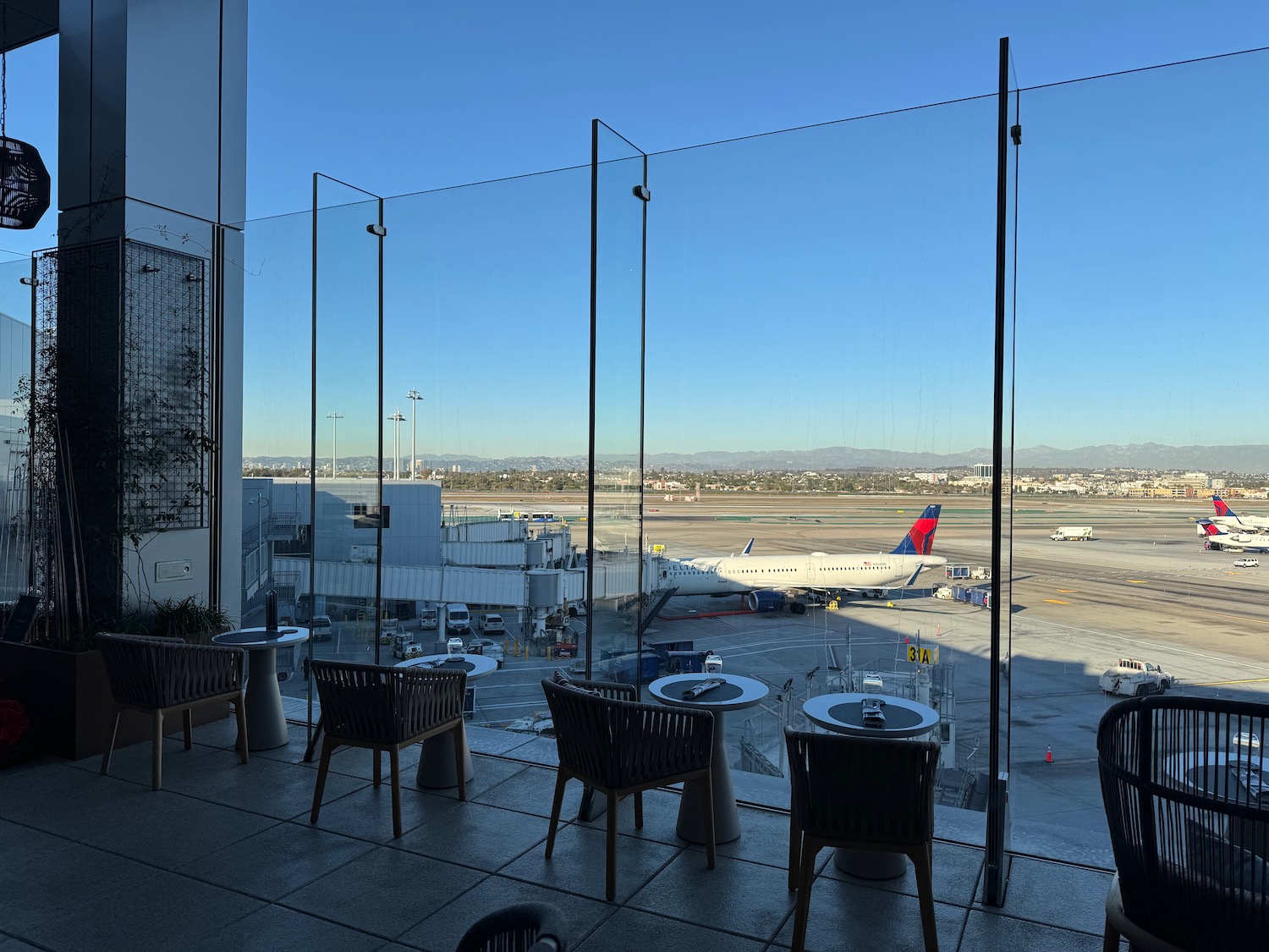 a glass wall with tables and chairs in front of an airport