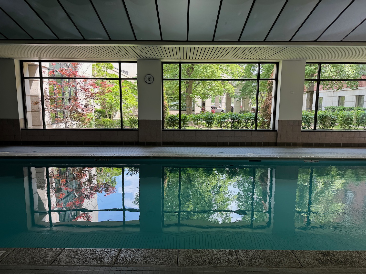 a pool with windows and trees in the background