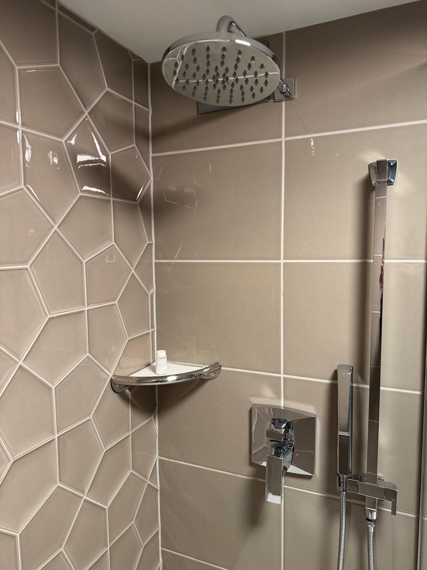 a shower with a shower head and a shelf