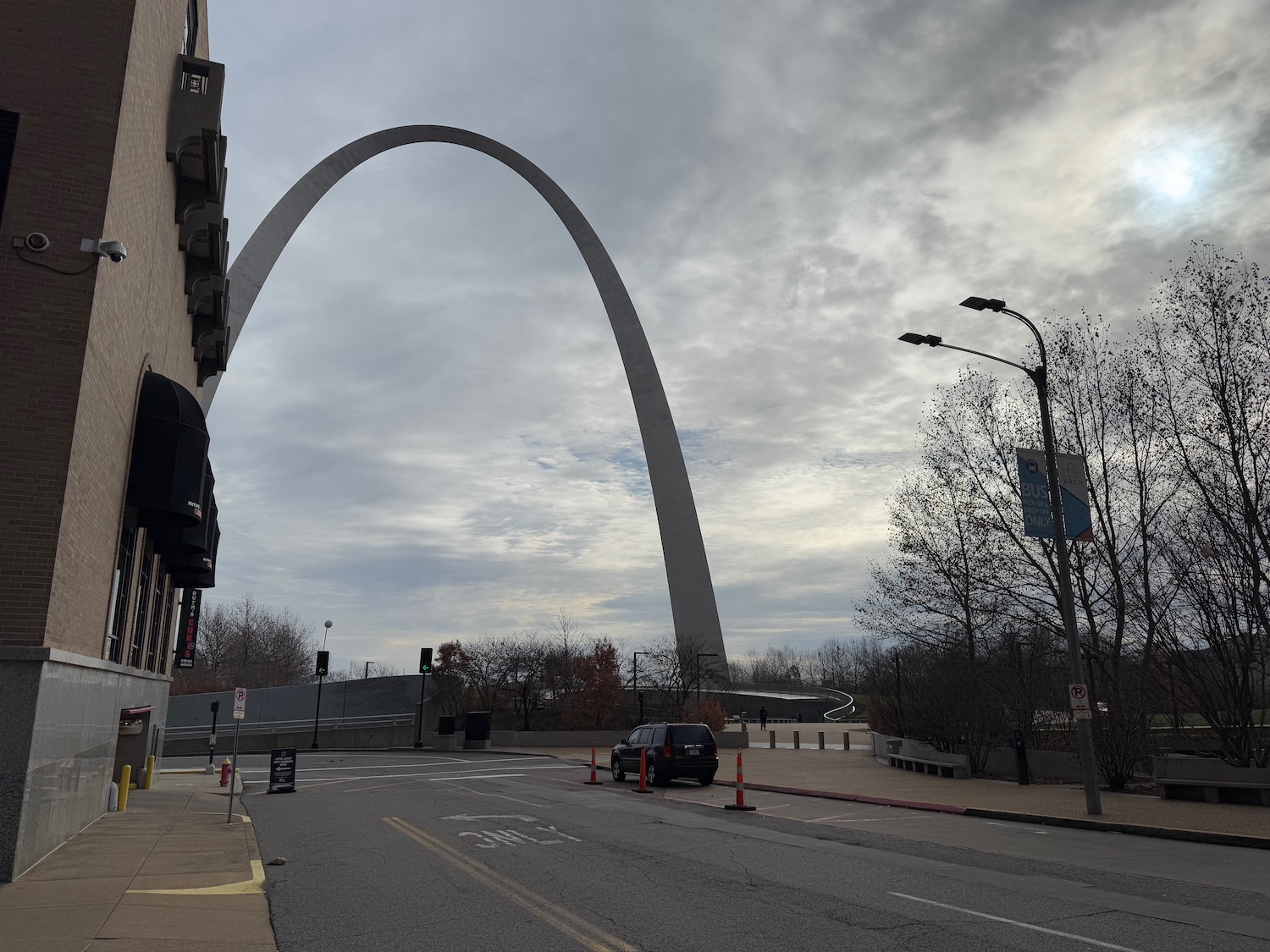 a large arch in the middle of a street with Gateway Arch in the background