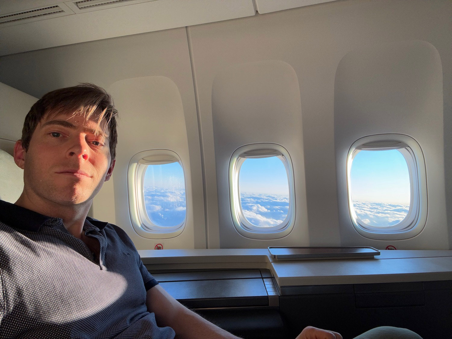 a man sitting in an airplane with windows and clouds in the background