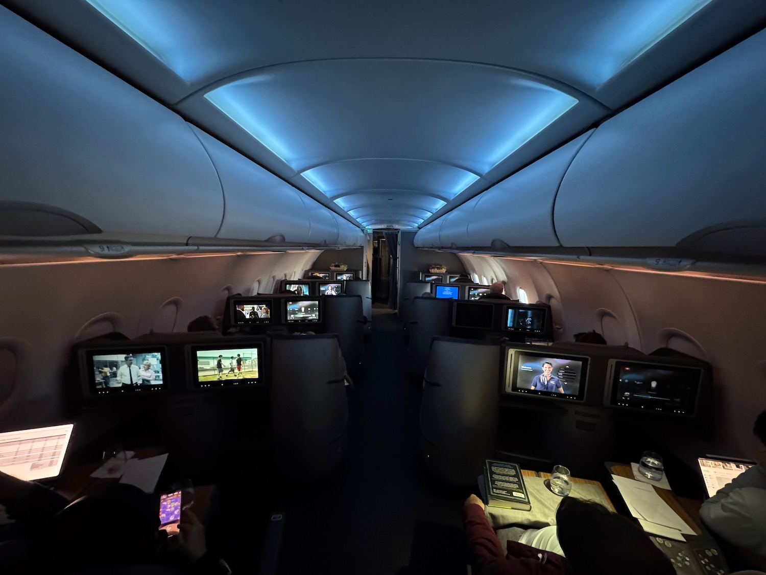 a group of people sitting in an airplane with monitors on the side