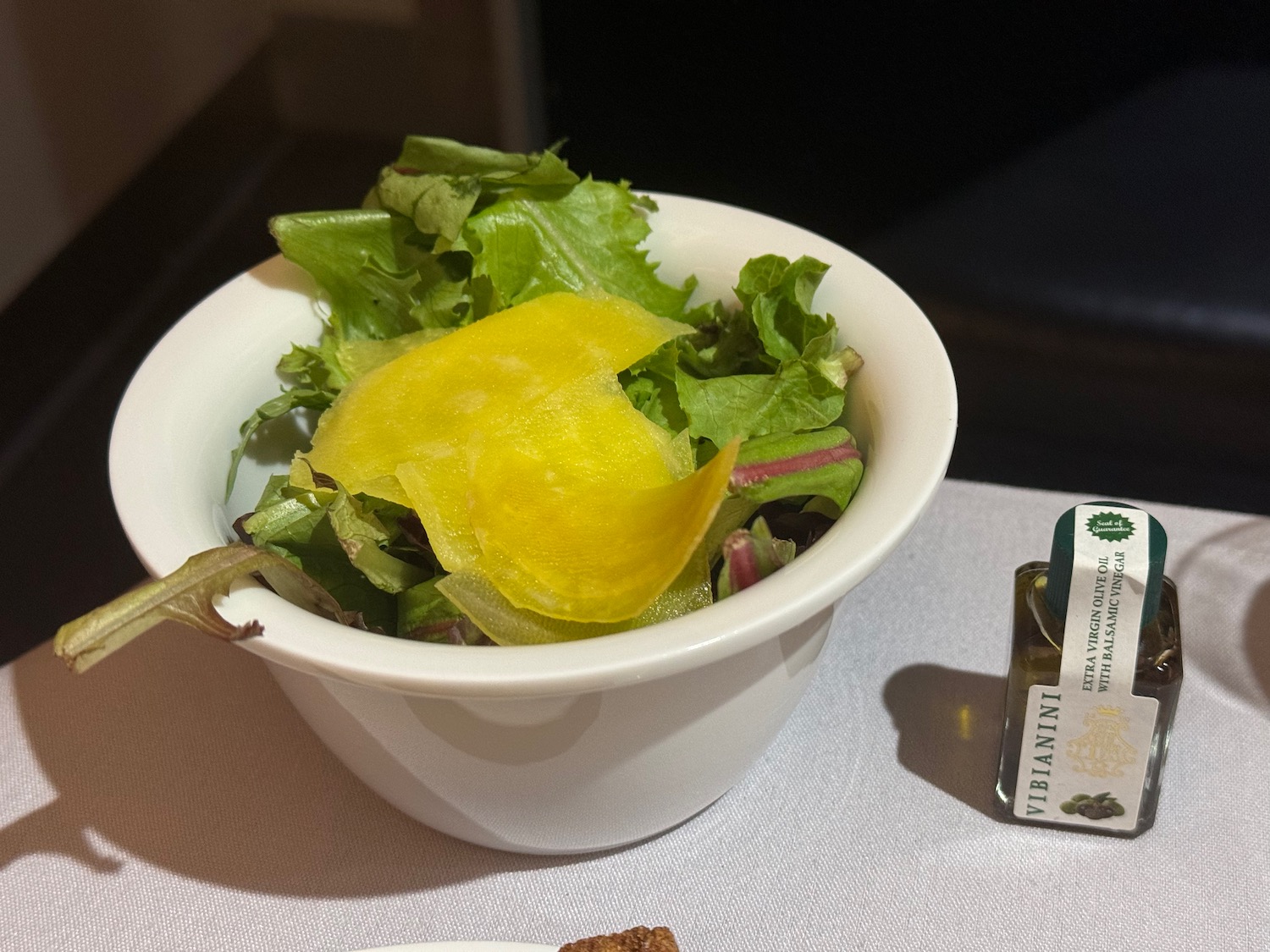 a bowl of salad with a yellow slice of potato in it