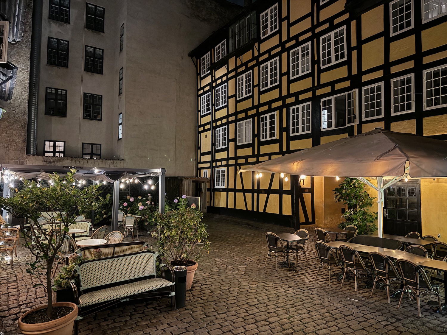 a patio area with tables and chairs and a building with windows