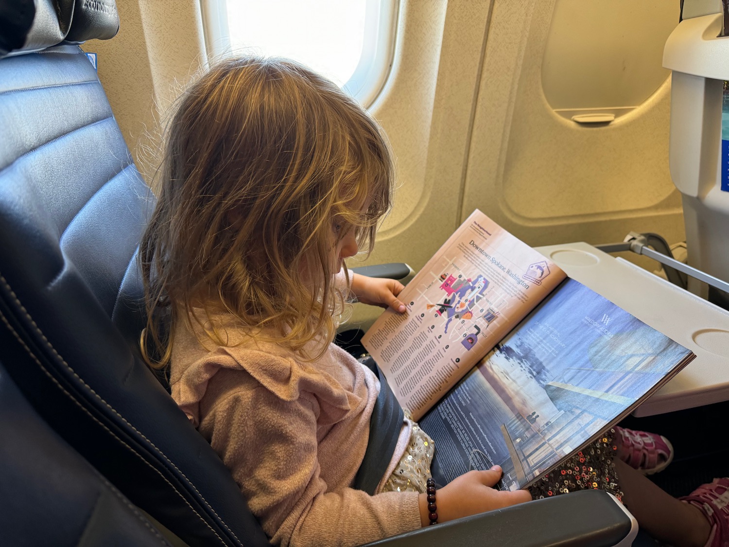 a girl reading a book on an airplane