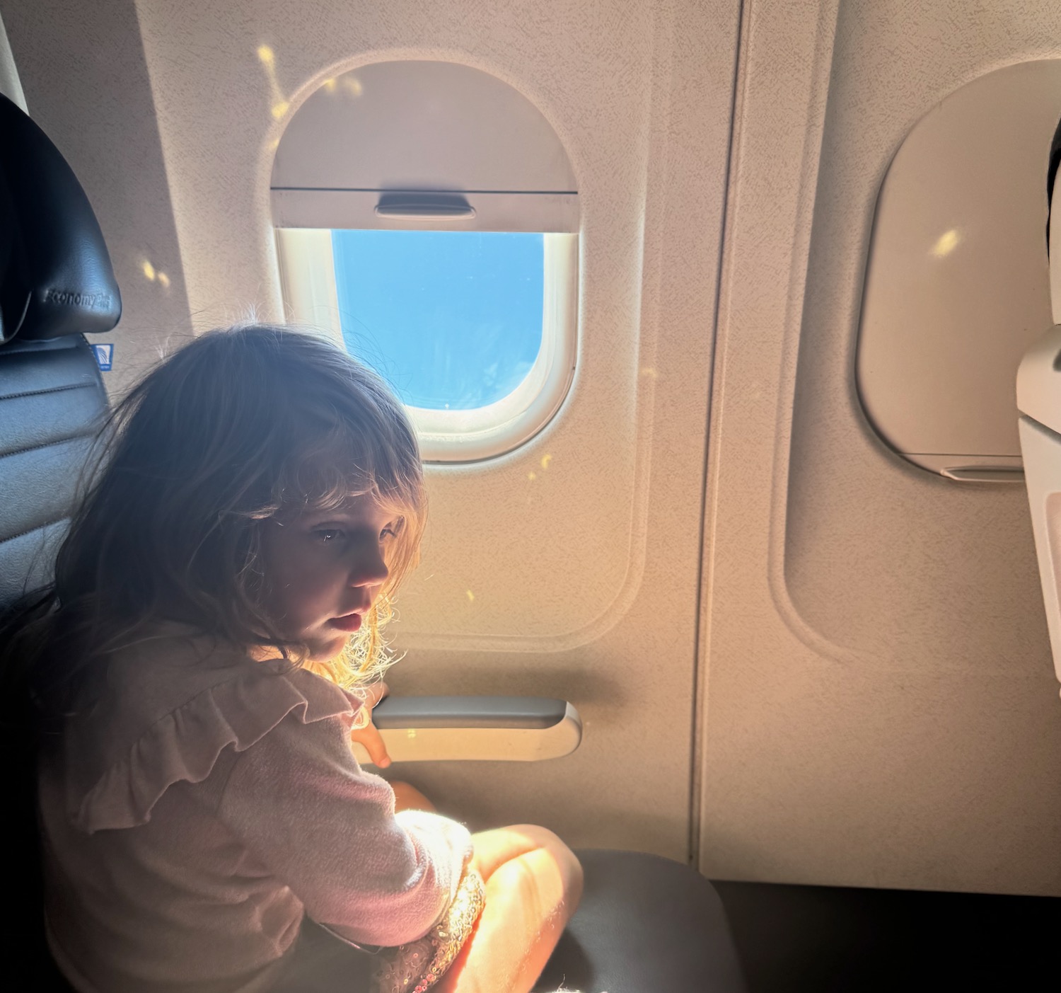 a girl sitting on a seat in an airplane