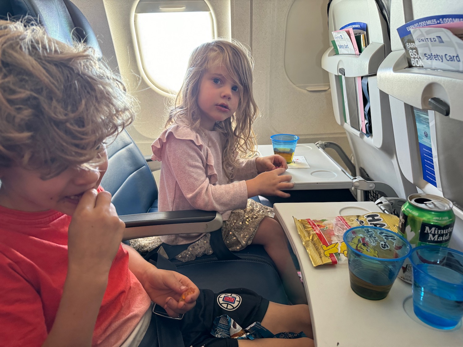 a boy and girl sitting on a plane eating