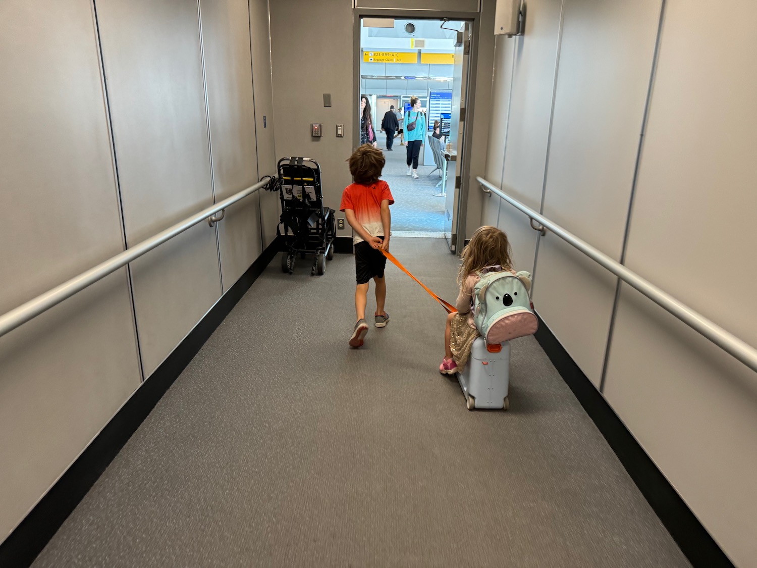 a boy pulling a suitcase with a girl on it