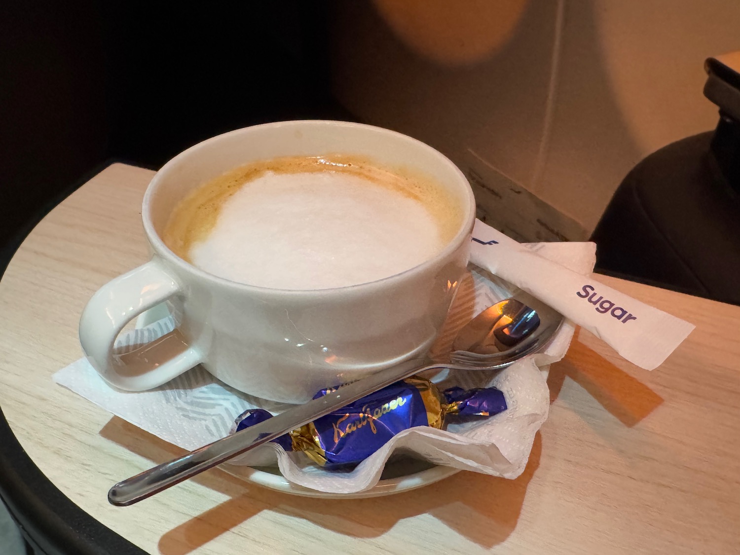 a cup of coffee with a spoon and candy on a plate