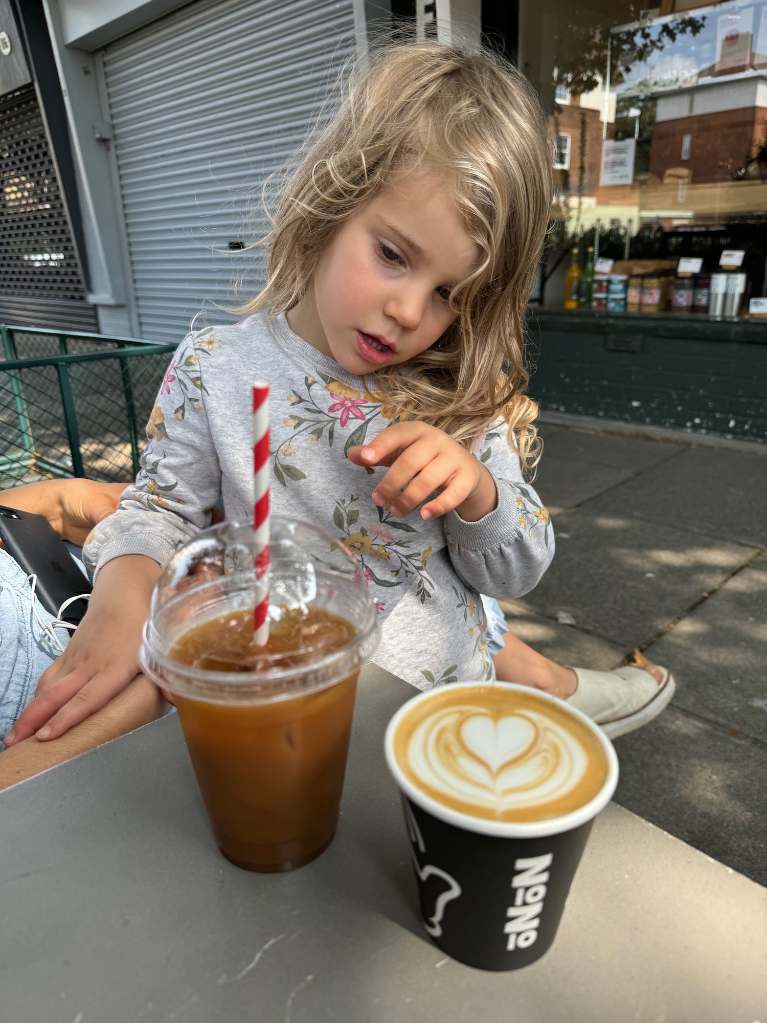 a girl sitting at a table with a drink and a straw