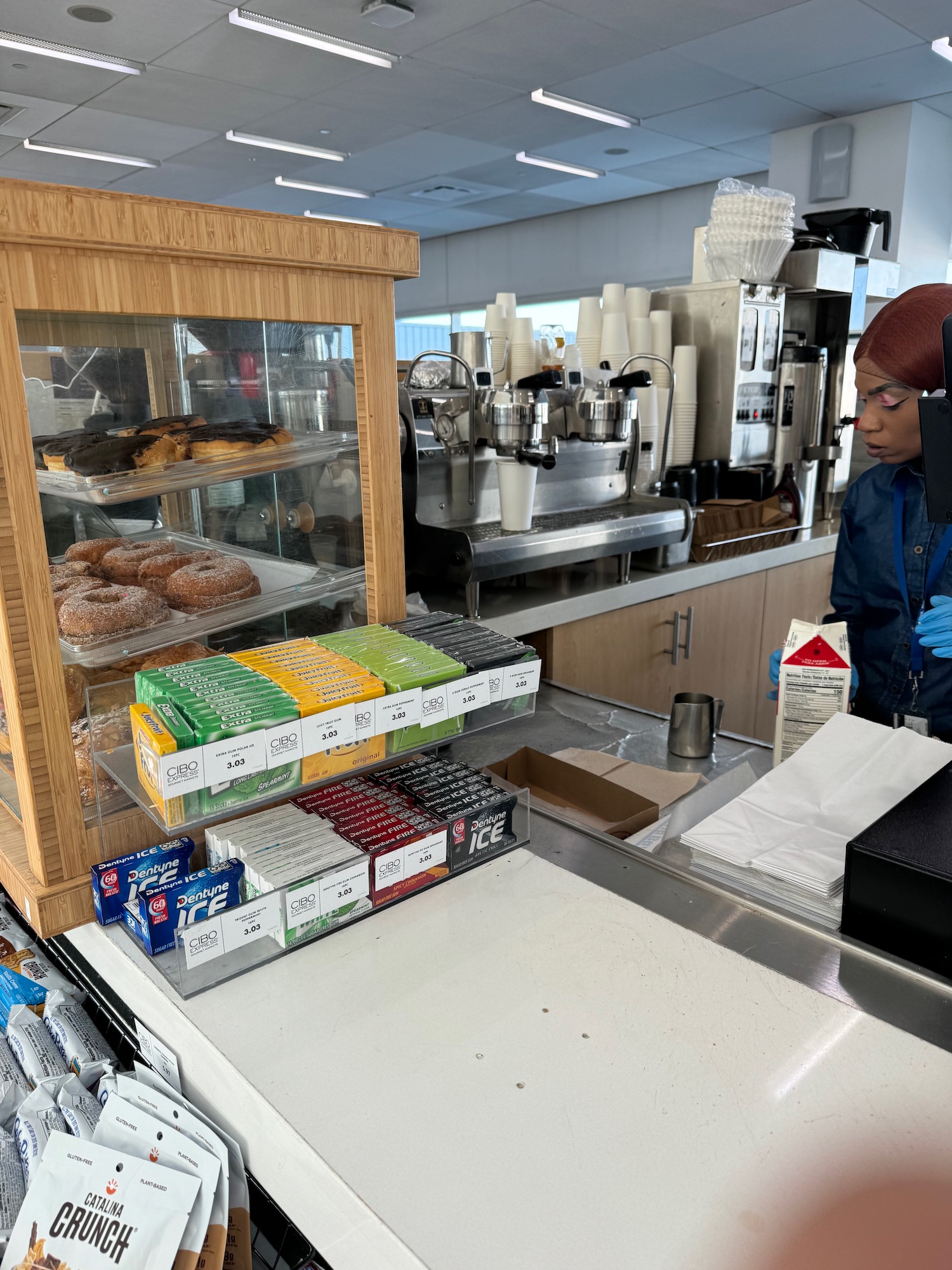 a woman standing behind a counter with a tray of doughnuts