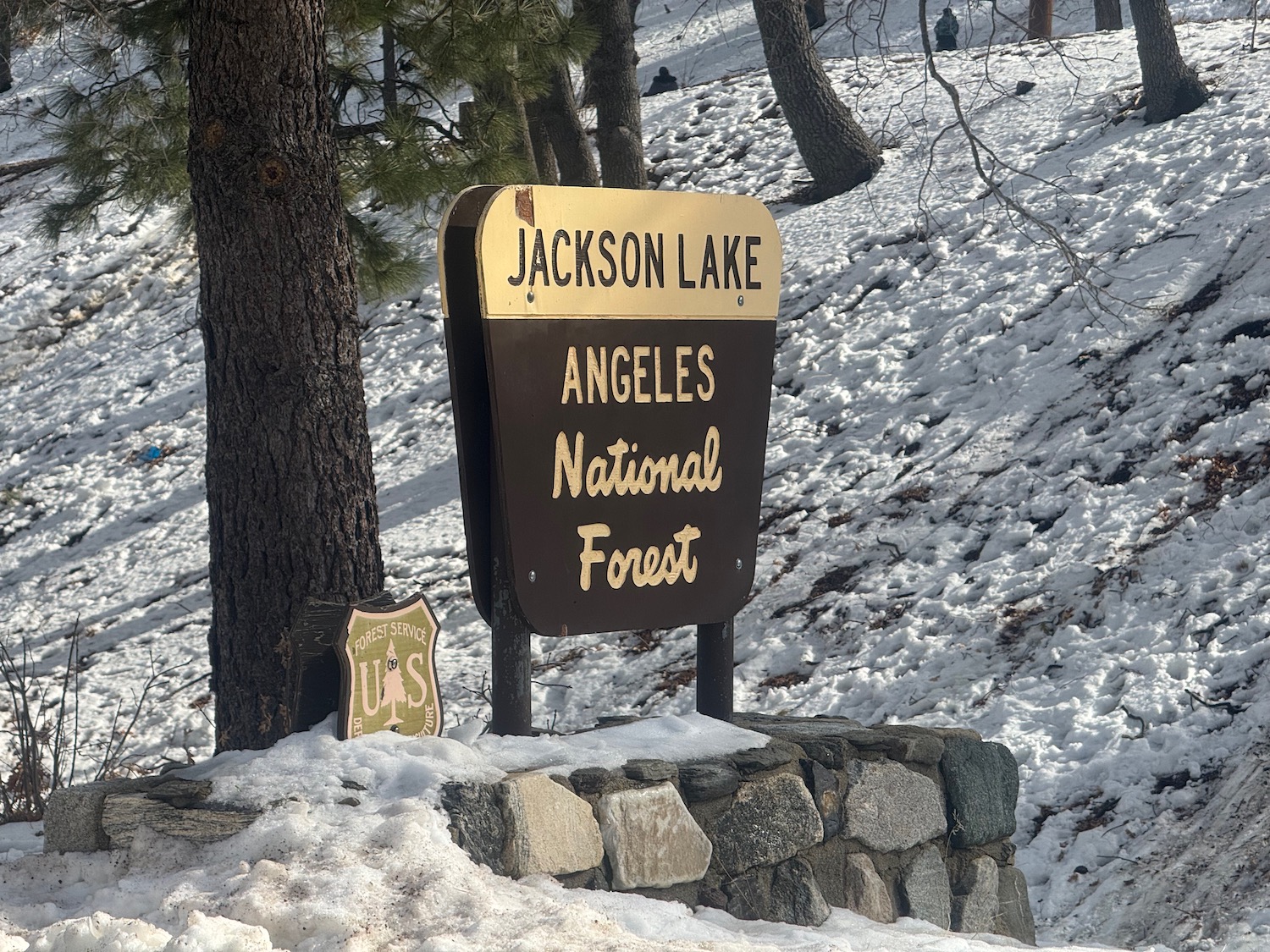 a sign on a rock wall with snow on the ground