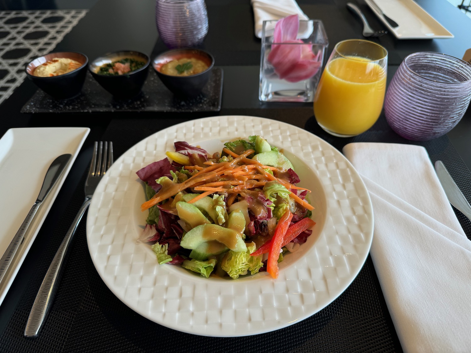 a plate of salad with orange juice and glasses on a table