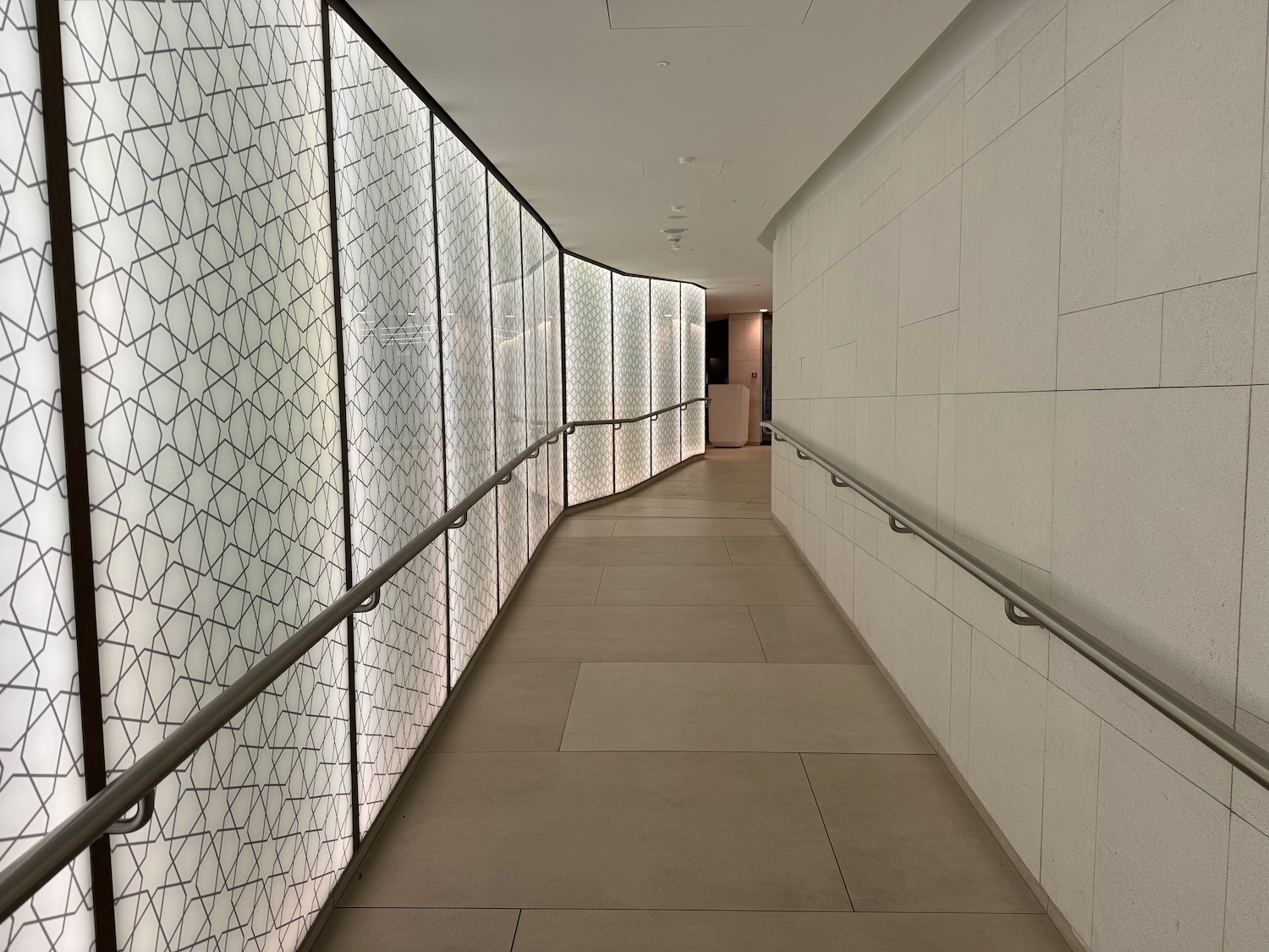 a long hallway with white walls and a metal railing