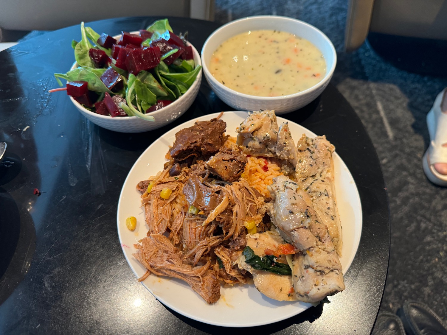 a plate of meat and rice with a salad in a bowl