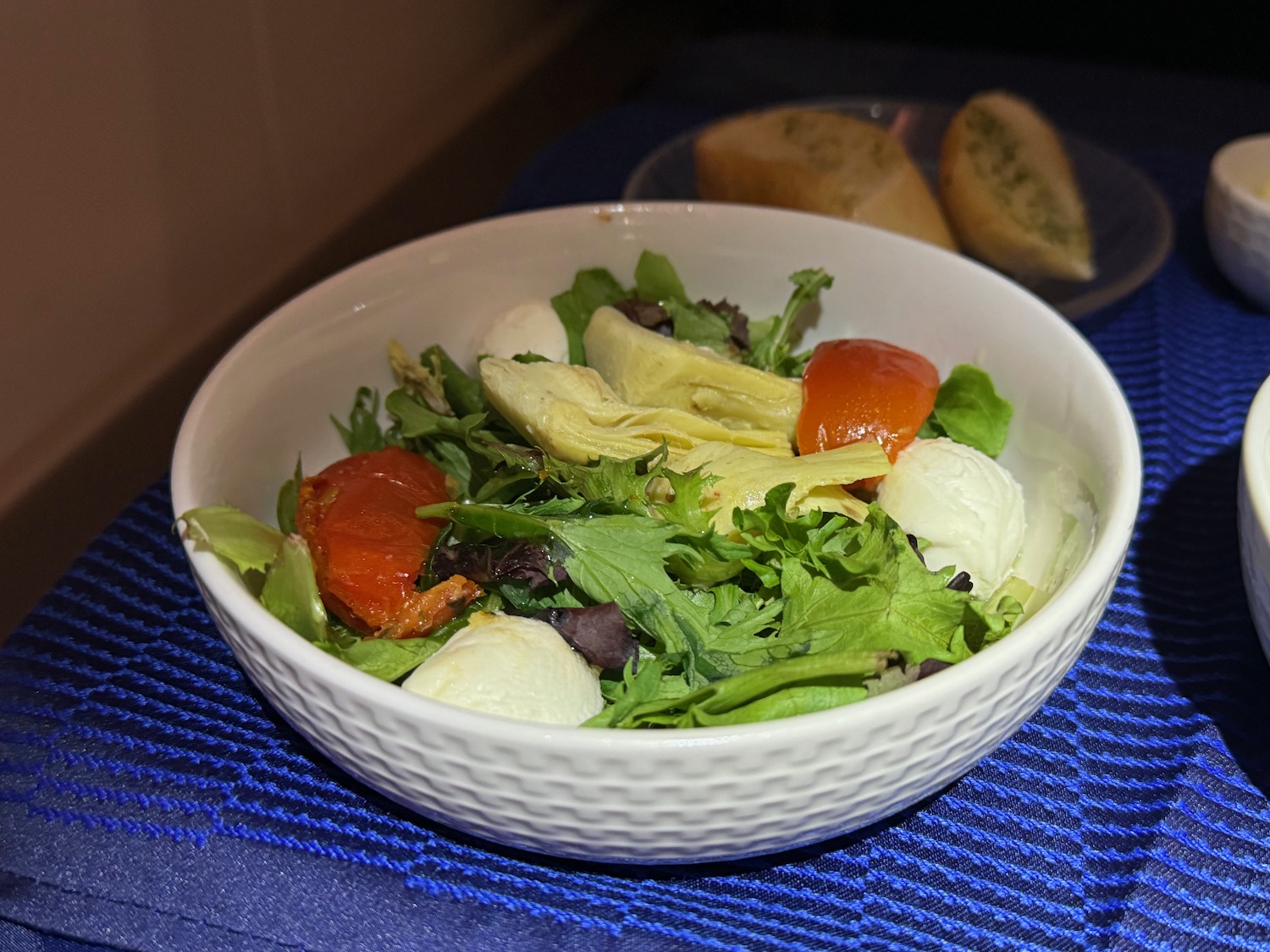 a bowl of salad on a blue place mat