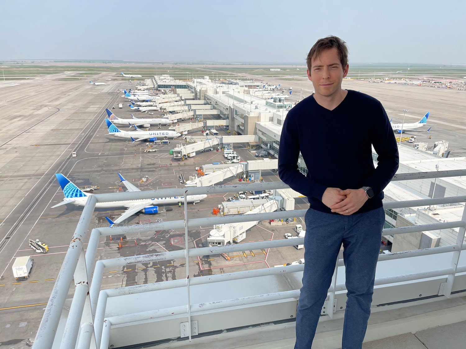 a man standing on a railing with planes in the background