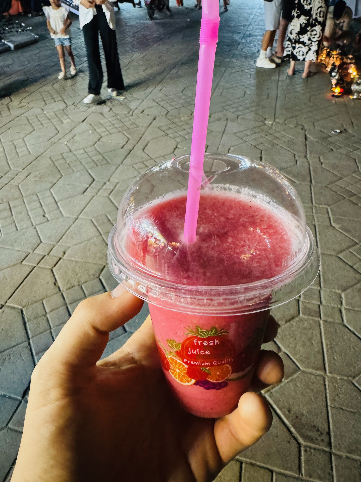 a hand holding a plastic cup with a straw and a pink drink
