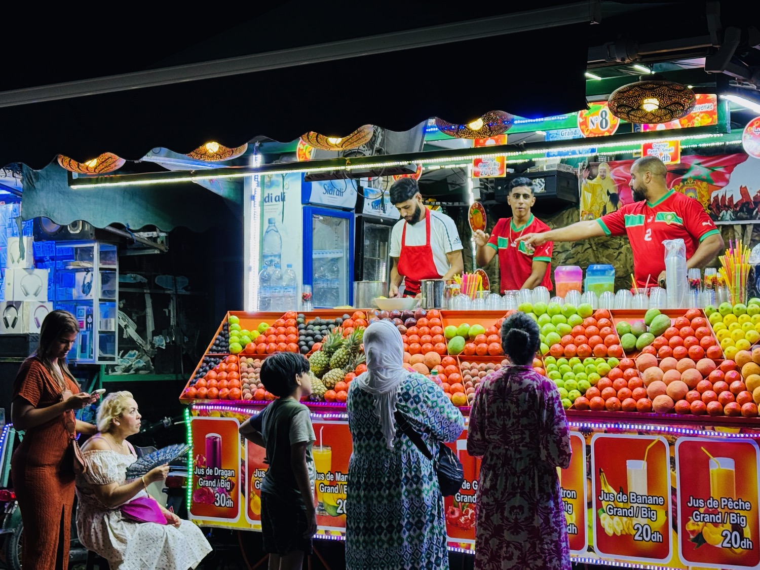 a group of people standing around a fruit stand