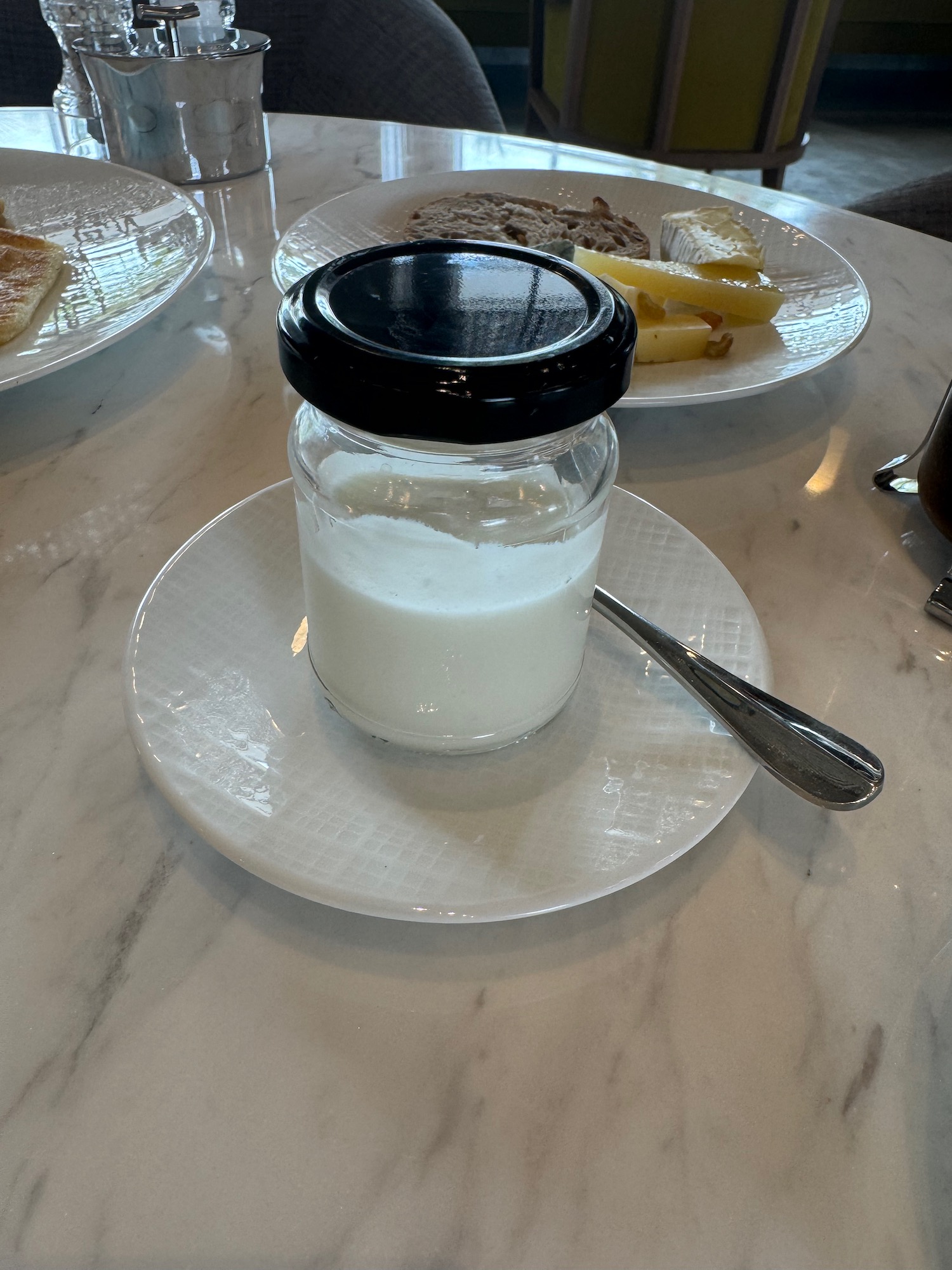 a jar of white liquid on a plate with a spoon