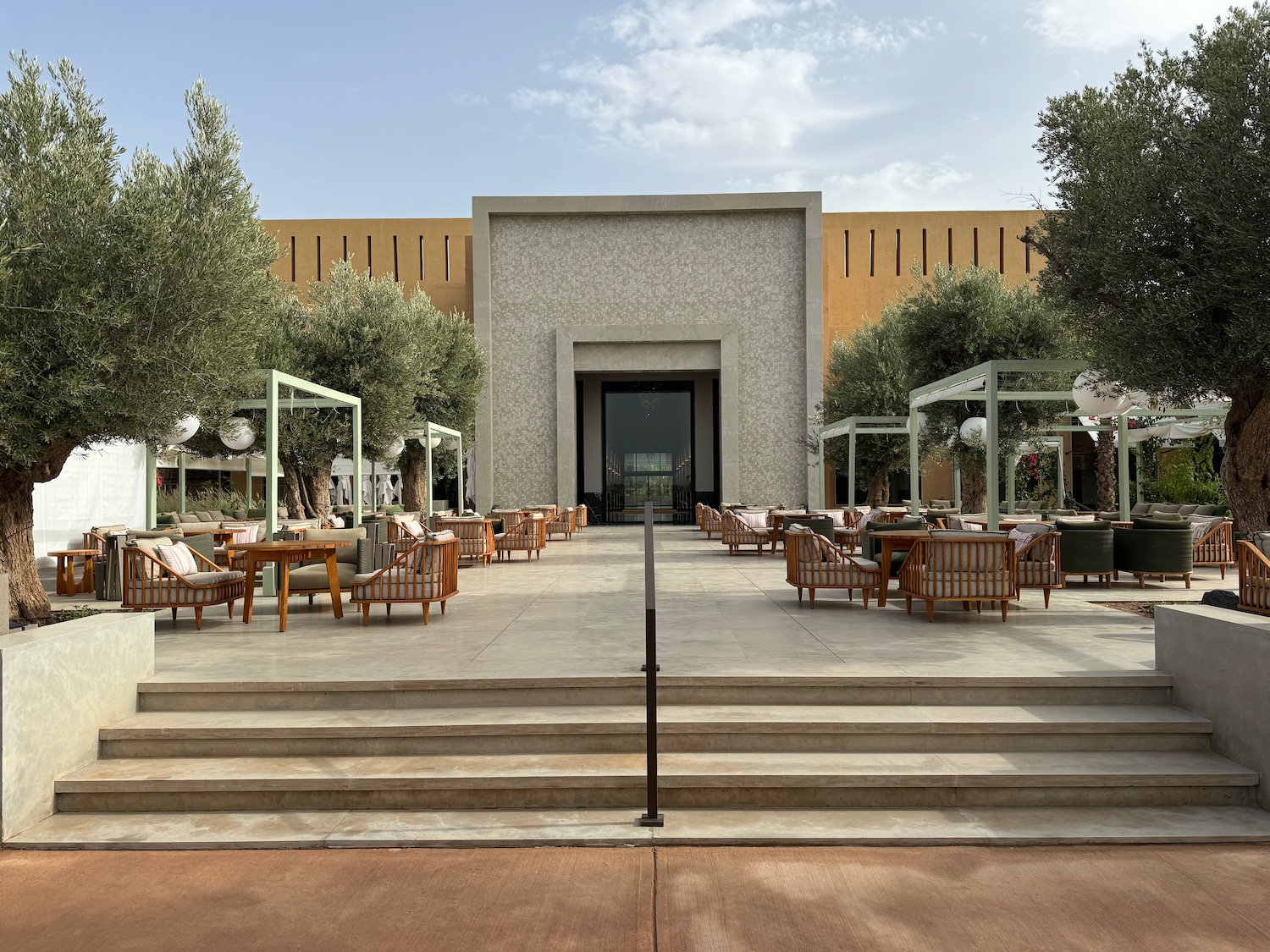 a patio with chairs and trees in front of a building