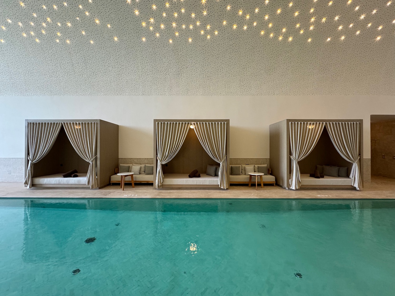 a pool with beds and lights from ceiling