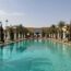 a swimming pool with palm trees and umbrellas