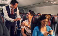 a man serving a drink to a couple of people on an airplane