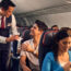 a man serving a drink to a couple of people on an airplane