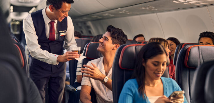 a man serving a drink to a couple of people on an airplane