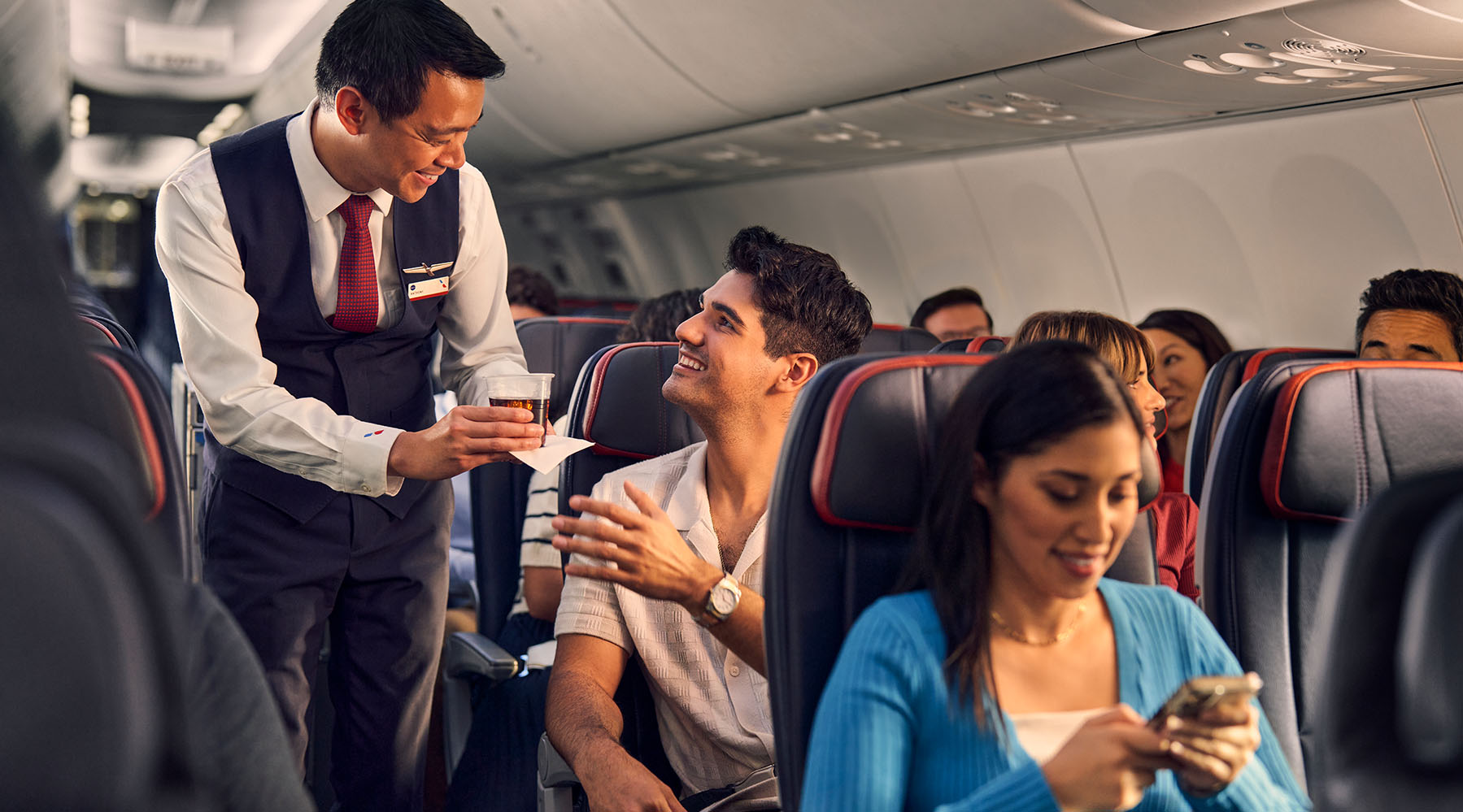 a man serving a drink to a couple of people on an airplane