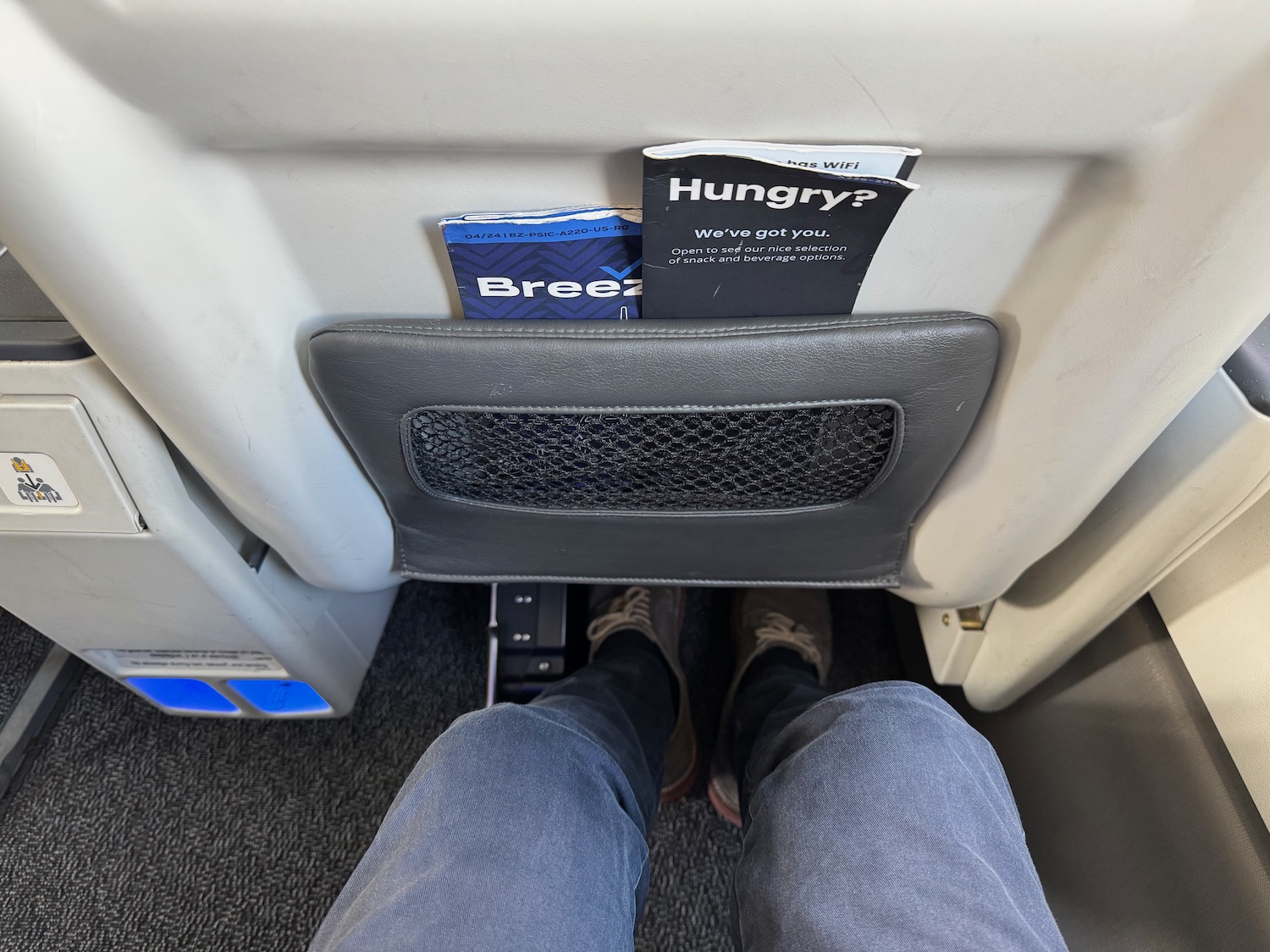 a person's legs in a seat with a pocket in the back